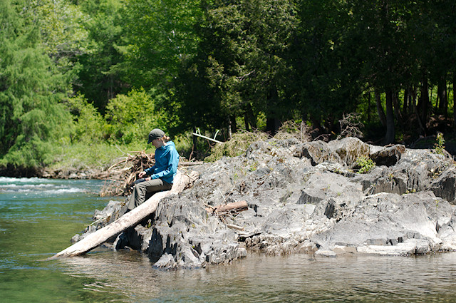 girl sitting on river rocks